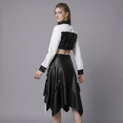 Woman wearing a black leather gothic skirt and white crop top on a gray background