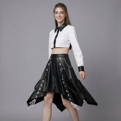 Woman wearing a white crop top and gothic black leather skirt with chain details on a gray background