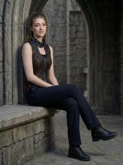 Seated model wearing black gothic leather vest with red lace-up corset sides, sleeveless punk waistcoat styling, and dark alternative fashion pants