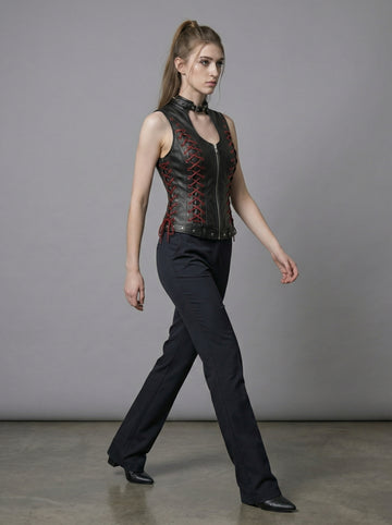 Black gothic leather vest for women with high neck collar, red lace-up side detail, sleeveless fitted corset style, and black pants in stone arch photoshoot