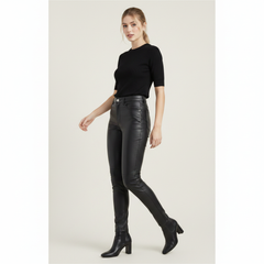 Woman wearing black leather pants and a black top on a white background
