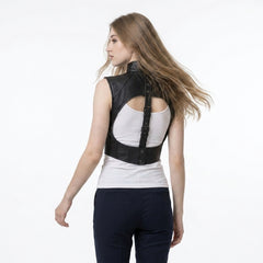 Front view of a women’s black leather gothic harness vest layered over a white tank top, with snap hardware details.
