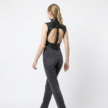 Women’s black leather cropped harness vest with high snap collar, open chest cutout, and structured gothic design.