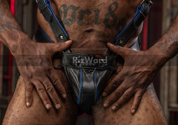 Model showcasing a black with blue piping leather bondage harness-Step into raw dominance with our premium black leather jockstrap and matching bondage chest harness. Built to enhance your physique and unleash primal energy in any dungeon scene, this rugged look is a must-have for hardcore kinksters.