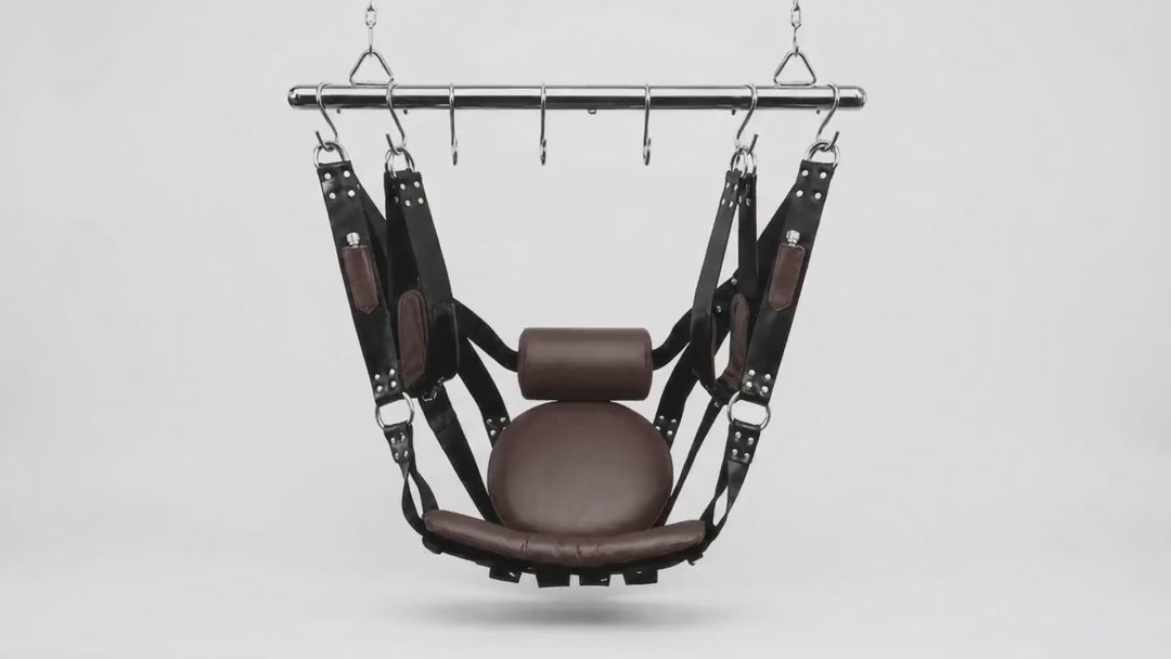 Black and dark brown padded leather sex swing hanging from a ceiling support rod with adjustable suspension straps