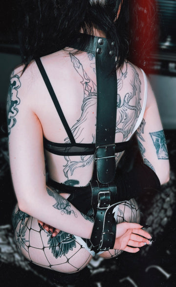 back view of a girl wearing a 2 piece back handcuff and neck collar restraints made with leather